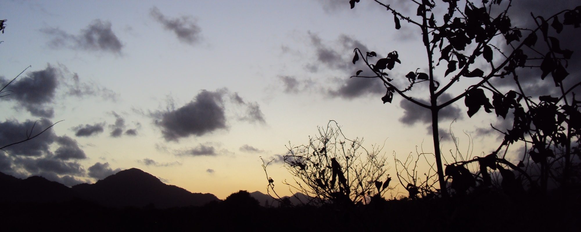 Entardecer na mata atlântica com céu e morros em clima sombrio.